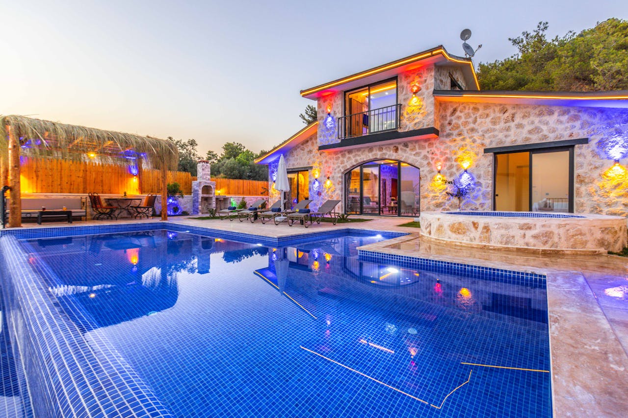 Elegant stone villa with illuminated facade, pool, and relaxing outdoor area.